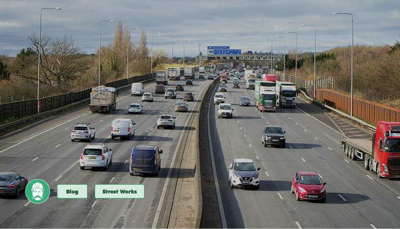 Highway maintenance works on a UK road with resurfacing equipment and traffic controls